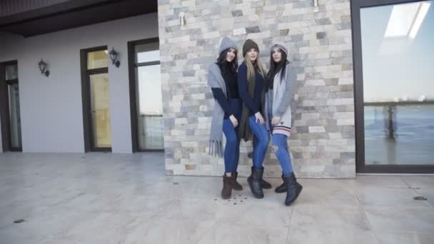 Tři hezké dívky do čepice a šála, Pózování na dvoře u domu — Stock video