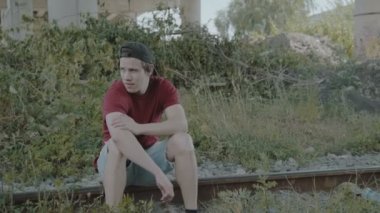 Düşünme ve şapkasını alarak yolda, oturan üzgün genç çocuk