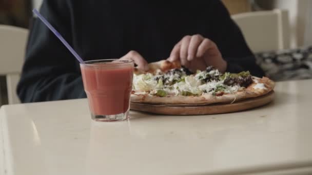 Jeune homme affamé mangeant insatiablement une pizza dans un café — Video