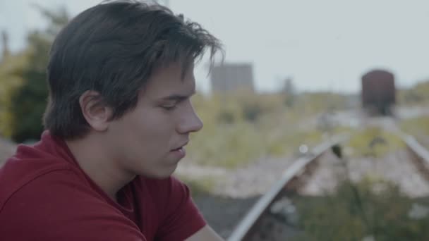Smutný mladík sedící na trati a myšlení — Stock video