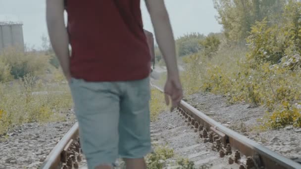 Молодий красивий хлопчик ходить по залізниці і думає. 4-кілометровий — стокове відео
