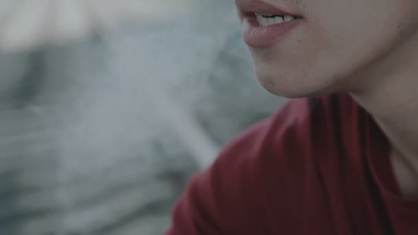 O rapaz pensativo jovem senta-se em um trilho e fuma o cigarro. Close-up. 4K — Vídeo de Stock