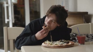 İnsatiably kafede bir pizza yemek aç genç adam