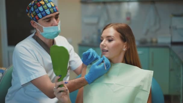 Zahnarzt zeigt das Ergebnis der Zahnreinigung seiner Patientin. 4k — Stockvideo