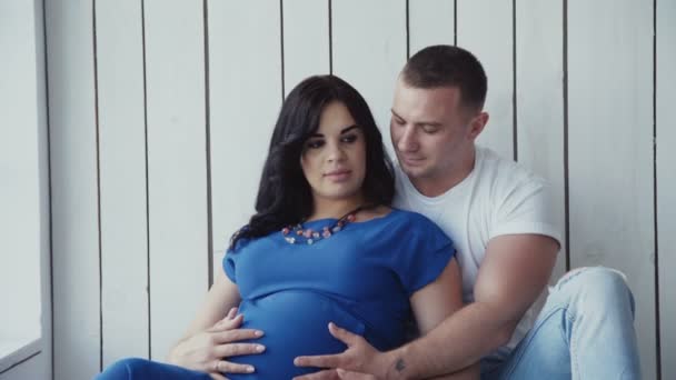 Mulher grávida e seu homem relaxar na camada na janela em casa . — Vídeo de Stock