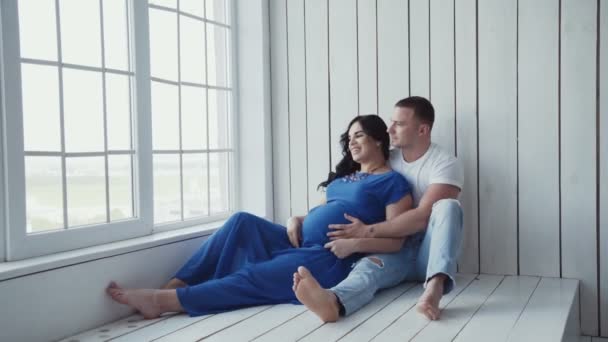 Hamile kadın ve onu adam evde pencerede katmanda rahatlayın. — Stok video