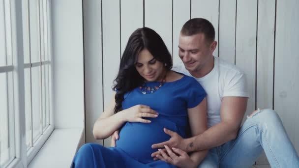 Έγκυος γυναίκα και ο άντρας της Χαλαρώστε στο στρώμα στο παράθυρο στο σπίτι. — Αρχείο Βίντεο