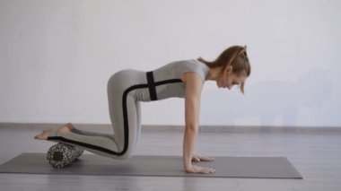Stüdyo spor silindir kullanarak güzel bir kız eğitim bacaklar kaslar görünümü