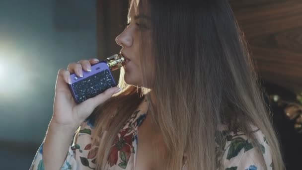セクシーな女の子のプロフィールは、猛烈に喫煙電子タバコ屋内 — ストック動画