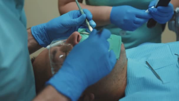 Dentiste avec assistant traiter les dents des patients avec une perceuse dentaire en clinique. 4K — Video