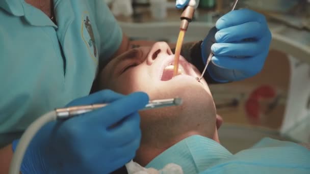 Дантист лечит пациентов зубами стоматологической дрелью в клинике. 4K — стоковое видео