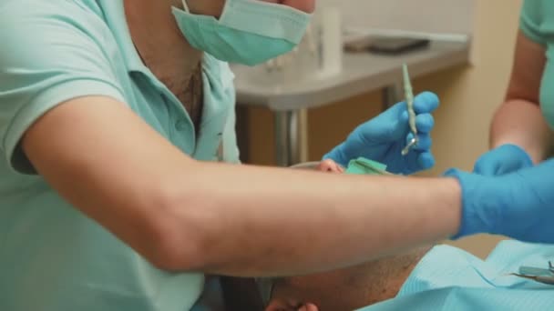 El dentista con asistente trata a los pacientes con dientes con taladro dental en la clínica. 4K — Vídeo de stock