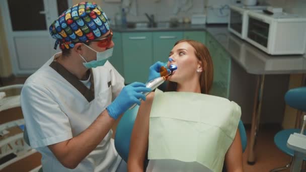 Chica bonita joven está en el gabinete dental en el tratamiento y la limpieza dental — Vídeo de stock