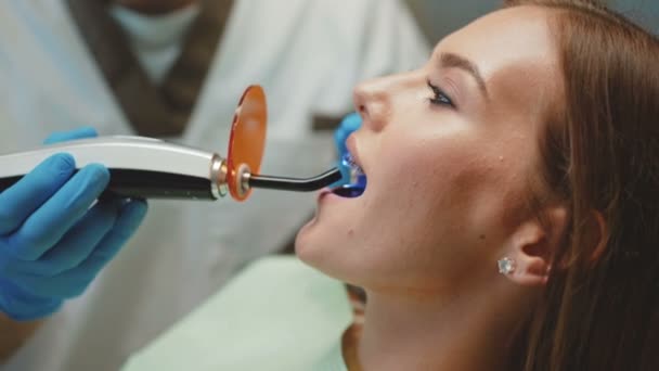 Mladá krásná dívka je v zubní kabinetu na léčbu a zubní čištění. 4k — Stock video
