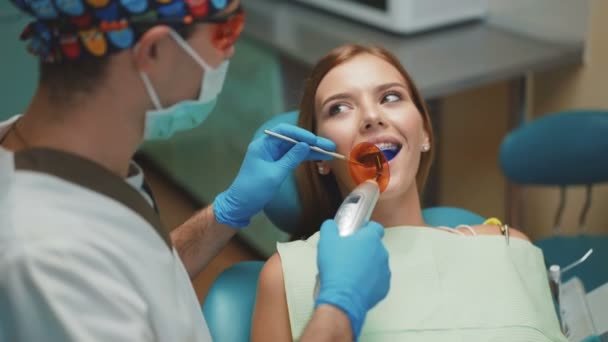 Jeune jolie fille est dans l'armoire dentaire sur le traitement et le nettoyage dentaire. 4K — Video