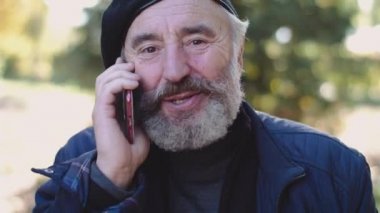 Mutlu kıdemli cep telefonda konuşan ve açık havada kameraya sevinir