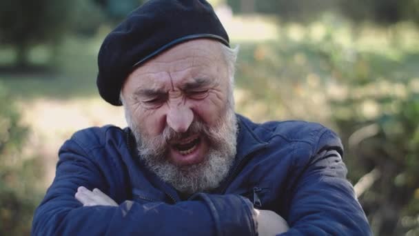 Aged senior massages chest from heart pain and speaks to passersby with smile — Stock Video