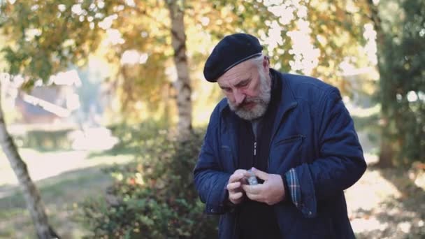 Одинокий пожилой мужчина глотает таблетки и сидит на уличной скамейке — стоковое видео