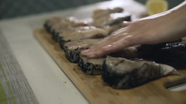 Las manos femeninas esparciendo especias en el filete de pescado en la tableta de madera. 4K — Vídeo de stock