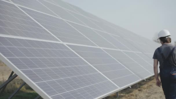 El ingeniero camina con las baterías solares y mira a su alrededor. 4K — Vídeo de stock