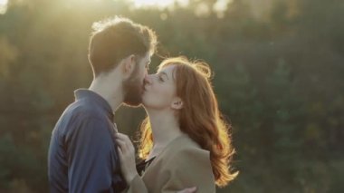 Mutlu çift kucaklama duruyor ve gün batımında birbirlerini öper