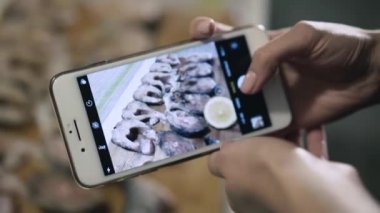 Kadın eller telefon kamera balık seti ile fotoğraf çeker