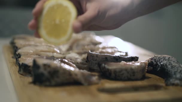 女性の手は、木製のタブレットにレモンジュースと魚のフィレットを注ぎます。4k — ストック動画