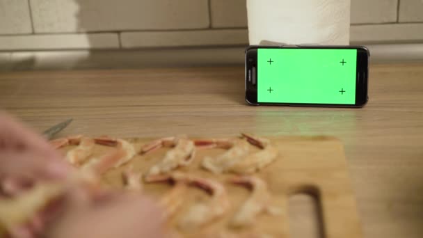 Huisvrouw peeling garnalen op smartphone met groen scherm — Stockvideo