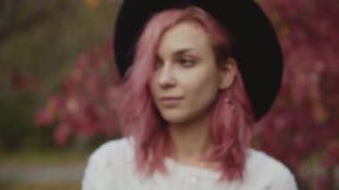 Renkli ağaçlarda duran güzel kızın kameraya gizemli bakışı