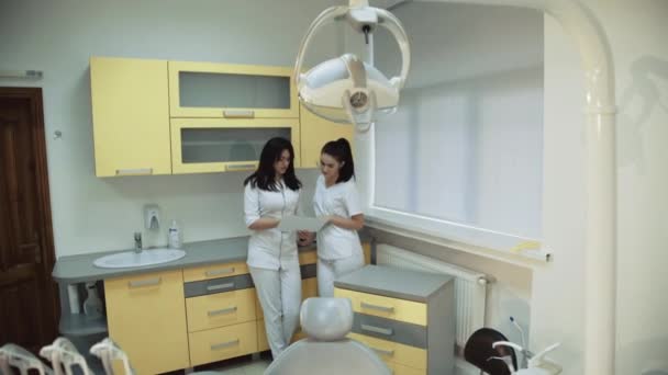 Due giovani dentiste si consultano in una stanza dentale. 4K — Video Stock