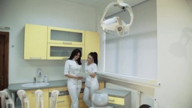 İki genç kadın diş hekimi diş hekimliği odasında danışır. 4k