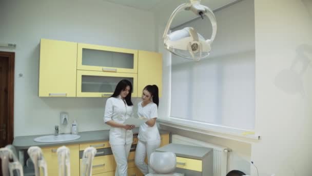 Dos odontólogas jóvenes consultan en sala dental. 4K — Vídeo de stock