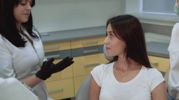Стоматолог молится о лечении, девушка улыбается на камеру. 4K — стоковое видео