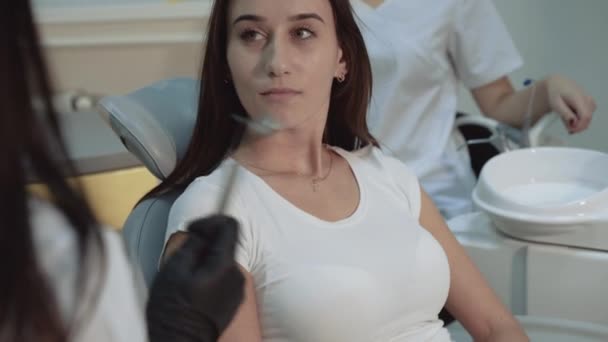 Красивая девушка слушать стоматолога консультации в кресле и улыбаясь. 4K — стоковое видео