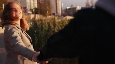 Mutlu çift akşam şehirde yürüyüş, el ele tutuşarak ve kameraya gülümseyerek