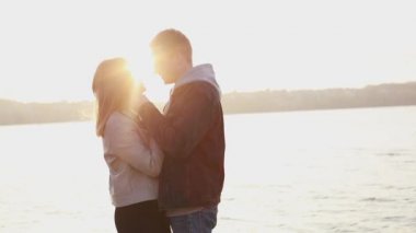 Mutlu romantik çift gün batımında kucaklar duruyor, adam kız öper
