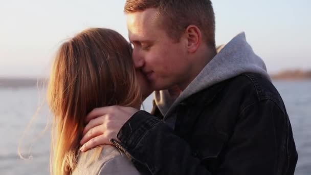 Romantisch paar staat in omhelzingen en kussen elkaar aan het meer — Stockvideo