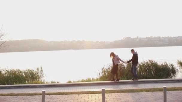 Romantisch paar op de avondwandeling aan het meer. Meisje leidt vriendje — Stockvideo