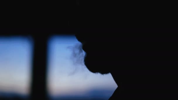 Een close-up silhouet van een bebaarde man die een sigaret roken. — Stockvideo