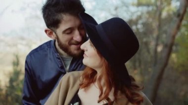Gülümseyen çift kucaklayan duruyor, adam güneşli parkta kız öpücük