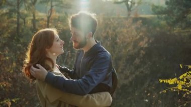 Güzel çift öpüşüyor birbirlerini ve güneşli bahar parkında kamera bakıyor