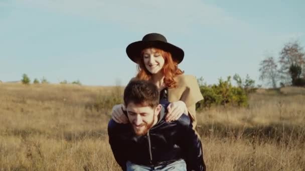 Hombre feliz llevando chica en hombros en la estepa, posando y coqueteando — Vídeo de stock