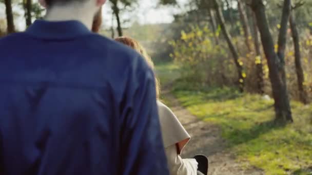 Jeune fille aux cheveux roux avec chapeau à la main flirtant avec son petit ami dans le parc 