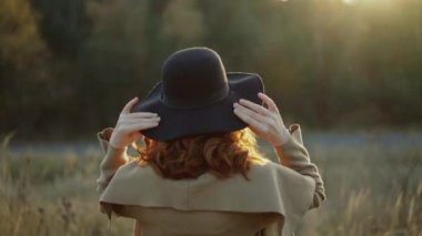 Kızıl saçlı Bayan Steppe yürür, şapka undresses ve gülümseme ile kamera pozlar