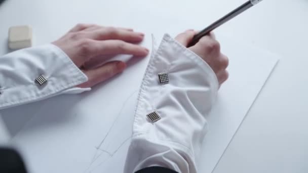 Top view of female hand drawing sketch of dress on white paper — Stock Video