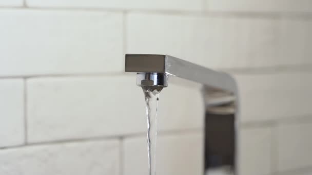 Wasserhahn auf weißem Fliesenhintergrund, von langsamem bis vollem Wasserdruck — Stockvideo