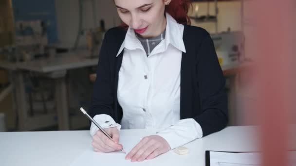 Desenho de desenhista de moda pensativo, feminino de um vestido na oficina leve — Vídeo de Stock