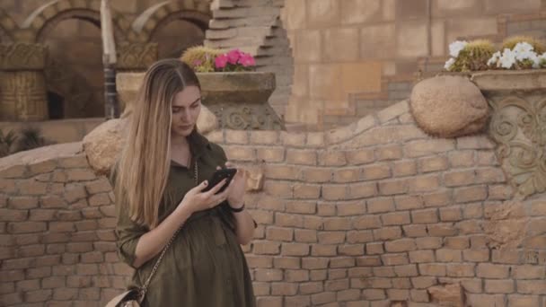 Mujer bastante embarazada usando teléfono inteligente en la mezquita — Vídeo de stock