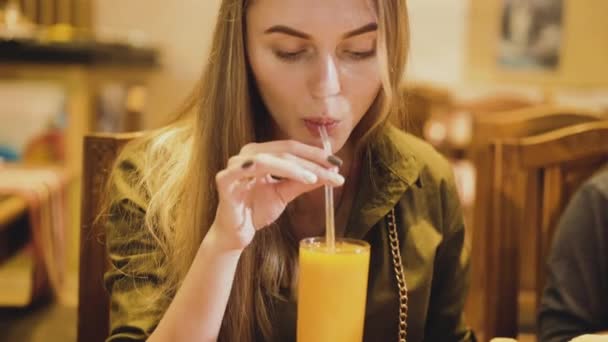 Pretty girl tasting the mango juice and rejoicing in cafe — Stock Video