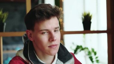 Bir gencin portresi ai cafede oturur ve kameraya bakar. 4k